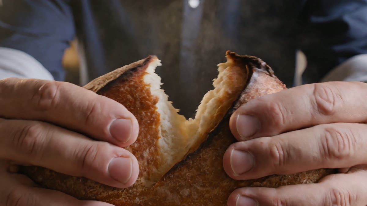 H&auml;nde reissen ein dampfendes, knuspriges Brot auf
